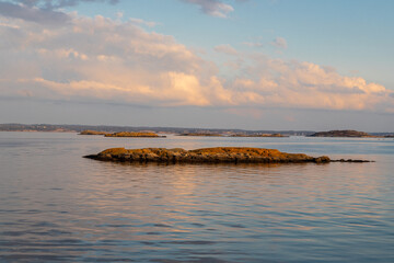 Beautiful summer evening with a spectacular sunset over the Gothenburg Archipelago and the calm water of the North Sea seen from the rocky coastline of the small island Vrango with a swimming jetty