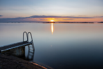 Beautiful summer evening with a spectacular sunset over the Gothenburg Archipelago and the calm water of the North Sea seen from the rocky coastline of the small island Vrango with a swimming jetty