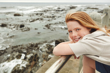 Beach, happy and portrait of child on promenade for summer vacation, getaway or weekend trip. Outdoor, relax and girl kid with smile on boardwalk by ocean for seaside view on holiday for travel.