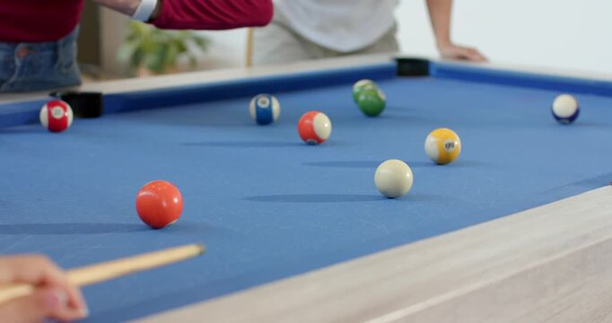 Woman in white mustard shirt lifting cue stick after balls scattering on pool table at home