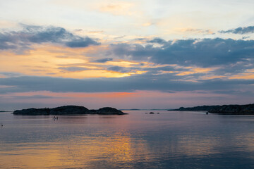 Fototapeta premium Colourful sunset over the Baltic Sea with and Swedish archipelago near Gothenburg, which is characterised by beautiful scenery and untouched nature with views on a wooden boardwalk to a small cottage,