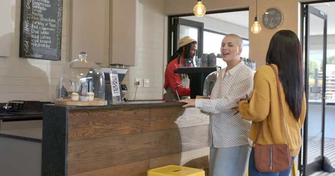 Diverse female friends approaching coffee counter ordering espresso getting cups to satisfy craving