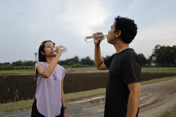 Woman and man drinking water after exercise