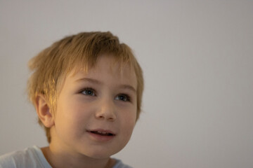 Young blonde boy looking up expressing curiosity and wonder
