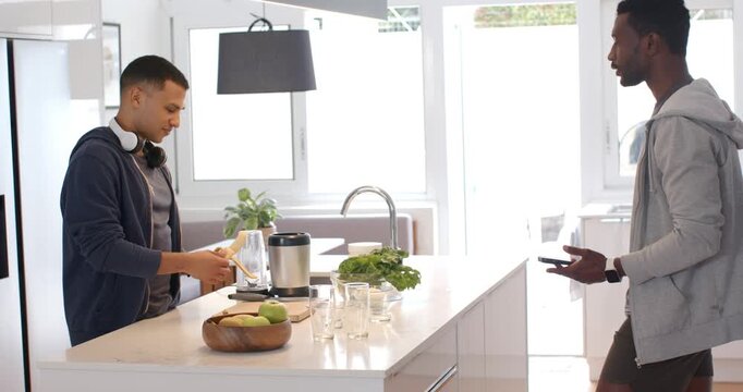 Diverse roommates following smartphone recipe peeling banana and layering produce at kitchen island