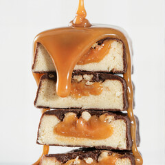 Pieces of protein bar stacked on top of each other with a caramel flavor and caramel dripping on them
