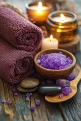 A spa treatment set with candles and terry towels, massage oil and stones, and purple salts.