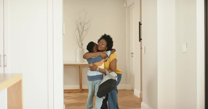African American mother arriving door carrying duffel bag, son running hugging mother speaking