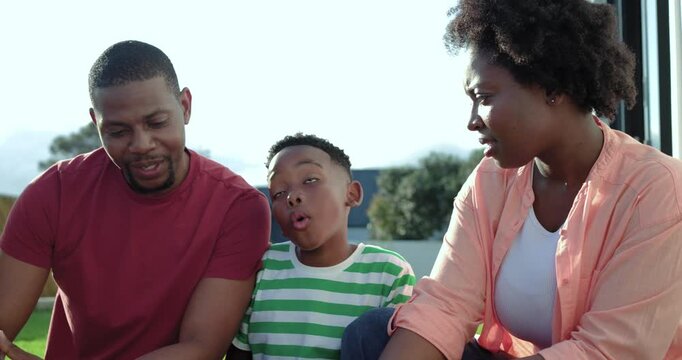 African American family sitting on front steps son sharing story parents leaning smiling