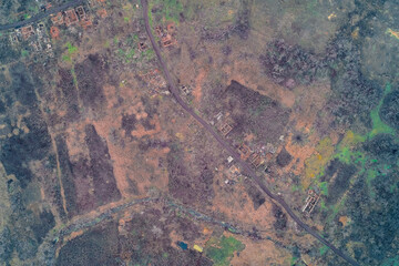 Aerial top down view of destroyed village ruins scattered along winding road. War zone civilian destruction and textured rural landscape background.