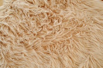 Close up texture of soft beige faux fur material with detailed strands and wavy pattern