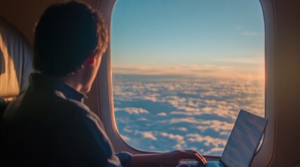 Man works on laptop while flying above the clouds during sunset