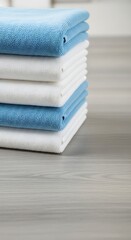 A stack of neatly folded textiles in alternating blue and white, resting on a wooden surface with a soft, blurred background