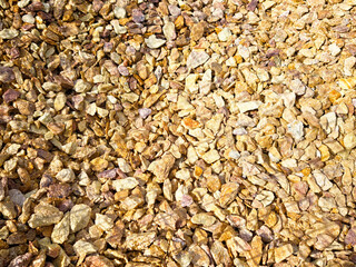 Textured surface of small golden stones in a natural setting with ample space for additional text placement