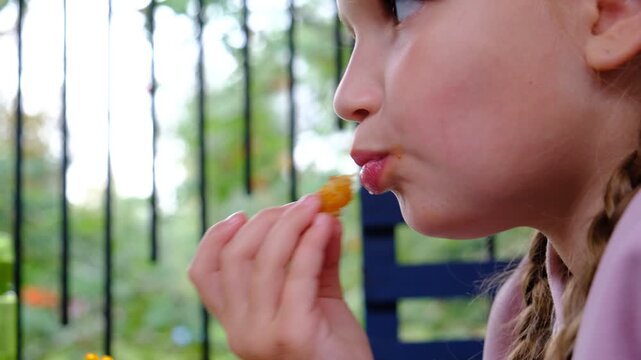 Little girl with family sitting at the table and eating  fried squid rings in cafe, tasty, enjoying. Real people, candid moments of joy.