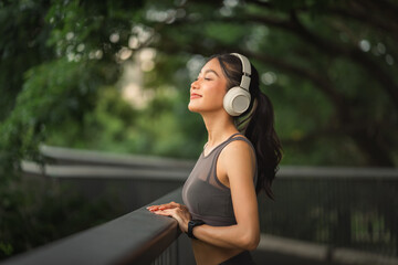 Woman relaxing with headphones outdoors, enjoying music and peaceful nature, calm lifestyle and wellness moment during outdoor workout break