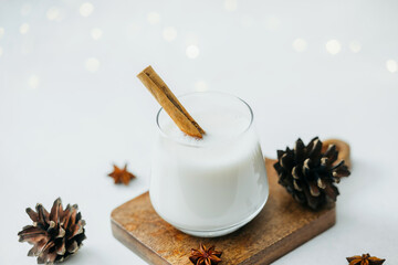 Creamy winter drink with cinnamon stick and pine cones, festive warm beverage
