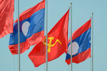 The Lao National Flag with the red flag with communist symbols of a sickle with a hammer flying in a blue sky, Laos