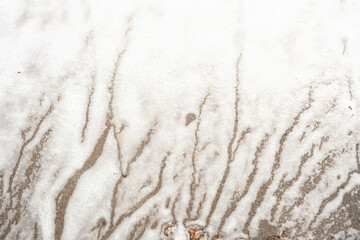 White foam covers ground with vertical flowing streaks creating natural abstract surface design