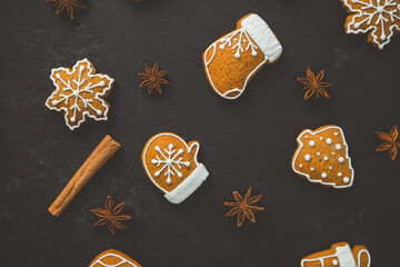 Christmas gingerbread cookies snowflake mitten tree shaped with anise and cinnamon stick on dark stone surface