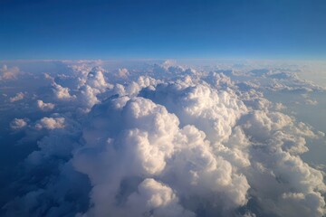 Fototapeta premium Aerial view of white fluffy clouds under a clear blue sky with sunlit edges