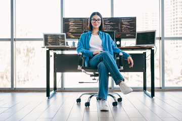 Female programmer in a modern office with multiple screens showing code and ideas