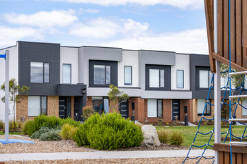 Modern townhouse residences facing a landscaped community playground. in a newly developed suburban neighborhood in Australia. Concept of family-friendly housing, child-friendly community design 