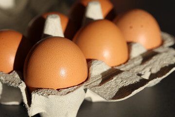 Close-up of fresh organic brown eggs in their box, bathed in the light of the morning sun and ready to cook.