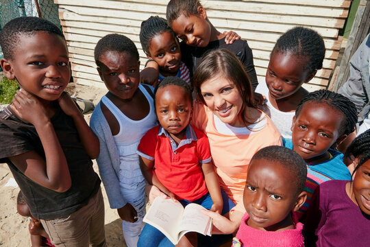 Reading, volunteer and portrait of children outdoor for ngo organization, education drive and support. Learning foundation, social responsibility and humanitarian with woman and kids for charity