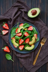 Fresh strawberry avocado spinach salad with golden fork