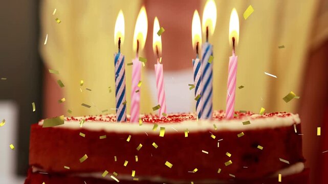 Gold confetti starting falling, cake five lit candles, person leaning with lighter for birthday