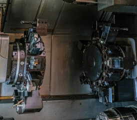 a complex industrial machine featuring multiple large, circular metal components with numerous bolts and gears. The machine parts are predominantly black and gray, with some silver accents