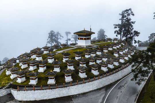 Aerial view of the Druk Wangyal Chortens stand in stark contrast against the misty backdrop, Druk Wangyal Chortens, Dochula Pass, Bhutan.