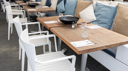 outdoor restaurant seating area with wooden tables and white chairs