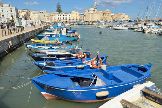 Traditional fishing boats mooring in Trani harbor Italy. Traditional fishing boats mooring in a picturesque harbor town with historic buildings. Puglia, Italy