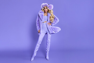 Happy Fashion Woman in Pastel Lilac Faux Fur Coat and Fluffy Earmuffs on Matching Purple Background, Cozy Winter Monochrome Beauty Portrait