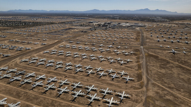 Aerial view of a sprawling expanse of retired aircraft glinting under the desert sun at the Davis-Monthan Air Force Base, a stark contrast against the arid landscape, Tucson, Arizona, United States.