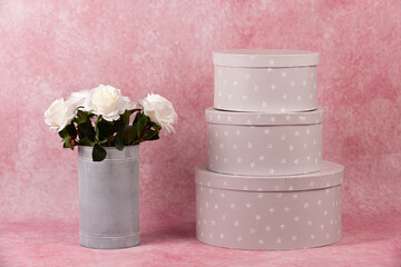 Florero con rosas blancas y cajas de regalo.