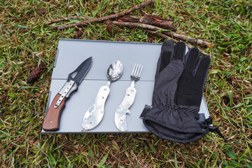 Outdoor gloves, a foldable spoon and fork, and a foldable survival knife commonly used for expeditions, mountain climbing, and camping, placed on a portable folding table.