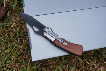 A folding knife for outdoor activities such as expeditions, mountain climbing, and camping placed on a portable folding table.