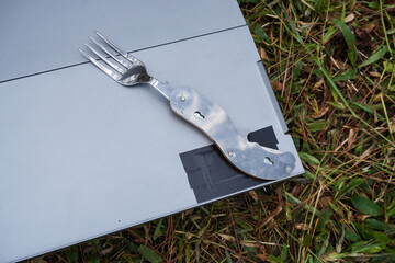 A foldable metal fork for outdoor and camping activities placed on a portable folding table.