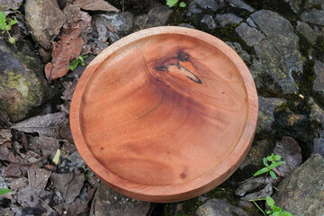 A wooden round plate placed on a rough stone surface. Flatlay high top angle view.
