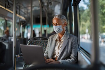 Businesswoman wearing a face mask working on a laptop during a city bus commute