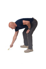 Side view of a bent man holding a paintbrush painting something imaginary on the ground