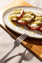 Italian caprese salad with tomatoes and mozarella. Pesto sauce and olive oil.