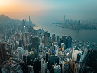 Aerial view of skyscrapers piercing the skyline, the harbor shimmering under a golden sunset, and Victoria Peak watching over the vibrant cityscape, Hong Kong Island, Hong Kong Island, Hong Kong.