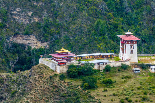 Aerial view of the Dobji Dzong fortress, its white walls and red roofs contrasting against the green hillside, Dobji dzong, Paro, Bhutan.
