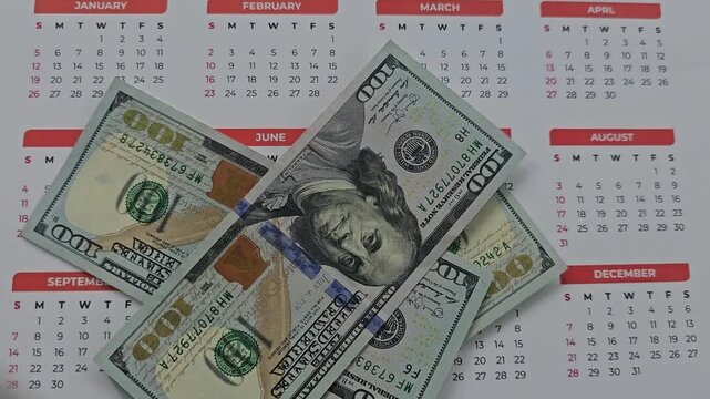 Calendar showing months from January to December with a hundred dollar bill placed on top