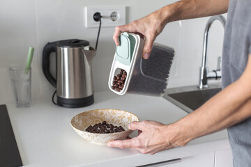 Man pouring chocolate cereal into a bowl in a modern kitchen, preparing breakfast at home, close up of hands, healthy morning routine, everyday nutrition, domestic lifestyle and casual cooking moment