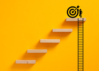 Person climbing ladder achieving goal on yellow background © Cagkan